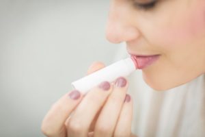 Image of a woman applying lip balm to her lips.