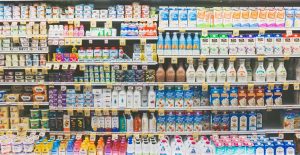 Image of hundreds of dairy products on a shelf in a grocery store. 