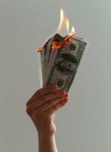 Image of a hand holding up burning money.