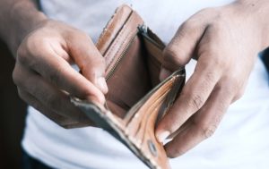 Image of man holding open a wallet with nothing inside. 