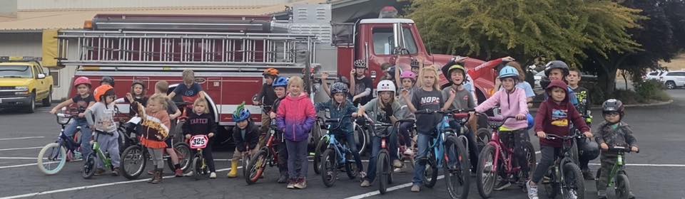 Image of kids on bikes in front of a fire truck