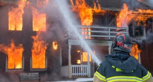 Image of a firefighter putting out a house fire.