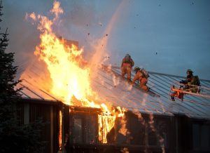 Image of firefighters on the roof of a burning building. 