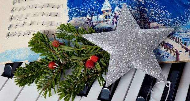 Image of a piano and sheet music with a Christmas theme.