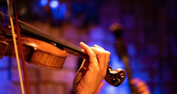 Image of a person playing a violin in a concert.