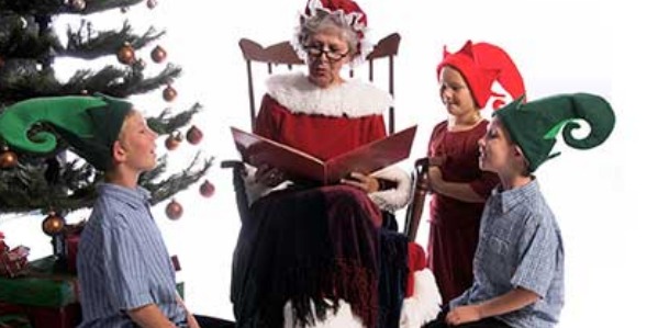Image of Mrs. Klaus reading a story to children wearing elf hats