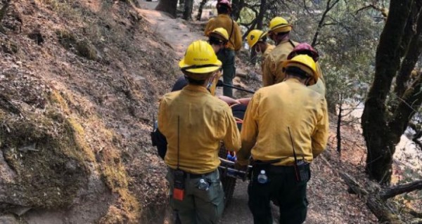 Image of USFS carrying a 29-year-old woman along the trail near Willow Creek in Bass Lake.