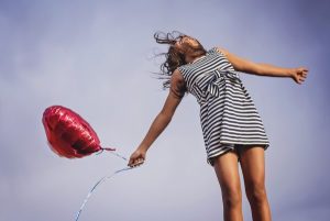 Image of a young girl holding a red balloon.