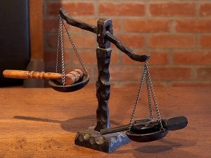 Image of the scales of justice with a gun on one side and a gavel on the other. 