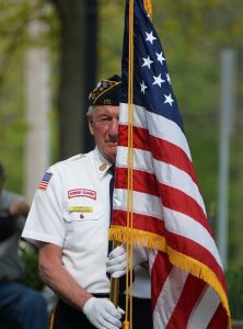 Image of a military veteran carrying an American flag.