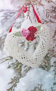 Image of a white, embroidered heart with flowers on it.