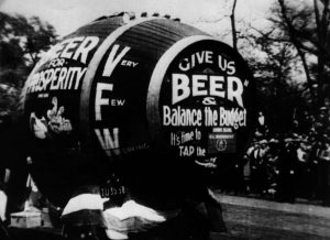 Image of a very large beer barrel with writing on the side that says, "Give us beer and balance the budget!"
