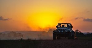 Image of a Jeep parked off road with the sunset in the background.