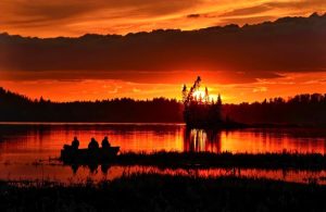Image of people fishing in boat at sunset.