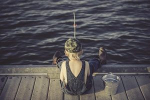 Image of a young boy fishing on a dock.