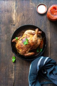Image of a roast chicken in a cast iron pan.