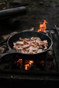 Image of bacon frying in a cast iron skillet.