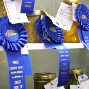 Image of jams and jellies with blue ribbons attached.