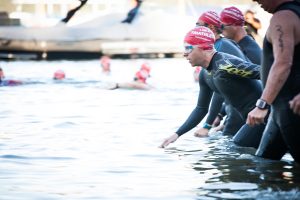 Image of swimmers entering the water at the start of a triathlon.
