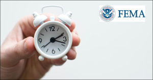 Image of a hand holding a small clock with the FEMA logo in the background.