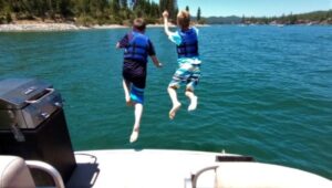 Image of two young boys jumping off a boat into Bass Lake.