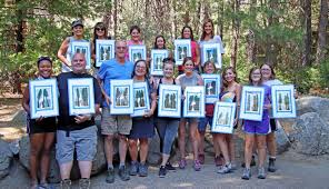 Group poses with paintings after the Paint and Sip session