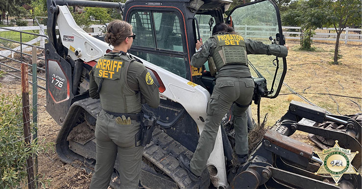 Members of the MADSET team inspect a recovered skid steer tractor