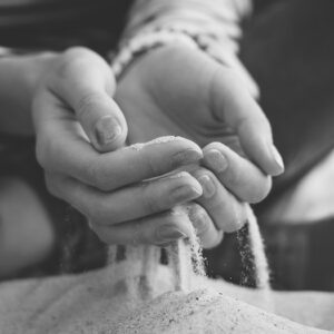 sand running through woman's hands