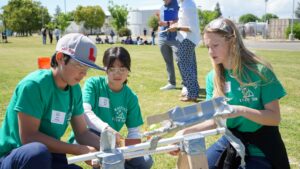 Picture of Mountain Home Surge Showdown team: 7th grade team members preparing their launcher during Surge Showdown.  Members include: Anadel Burrow, Ezra Donker, Mercy Kim.  Coached by Kim Meeks.